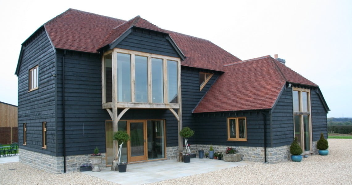 New house with larch cladding and red tile roof. Picture windows at front